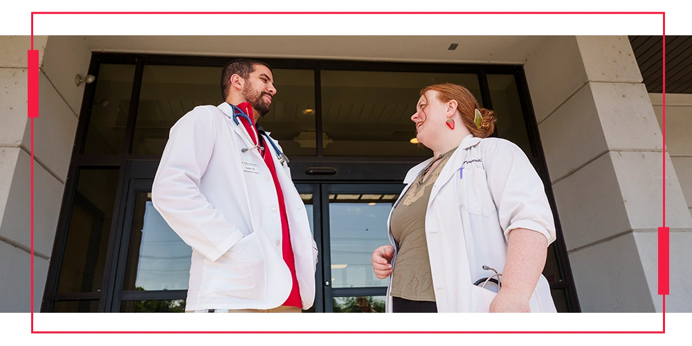 image of a male and female doctor conversing in front of a hospital doorway